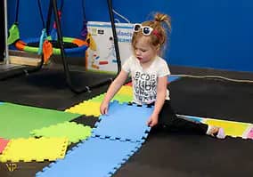 Child setting up floor mats in the sensory gym.