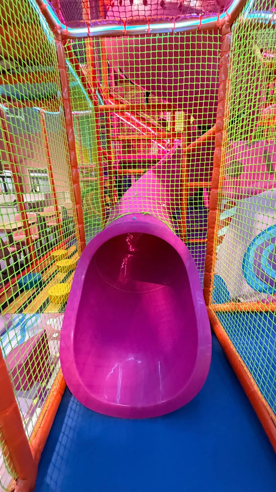 Bright pink tube slide inside the play structure at Candeeland Modesto.