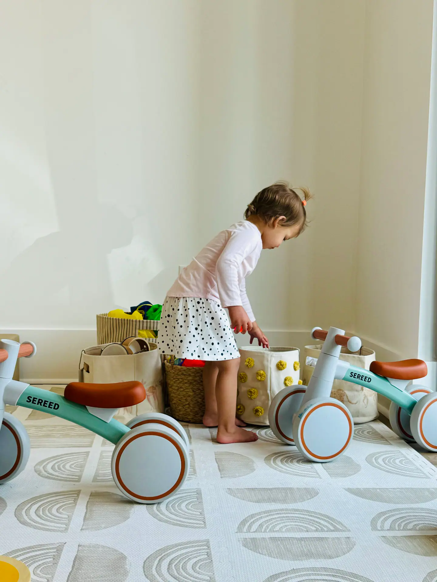 Toddler exploring a calm play nook with ride-on toys and baskets at Create & Play Club.