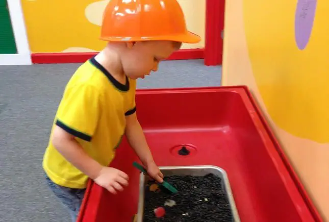 Child exploring a discovery-style play station at Whiz Kids Naples.