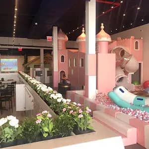 PeekabooO's pastel castle-style indoor play structure with slide and ball-pit area.