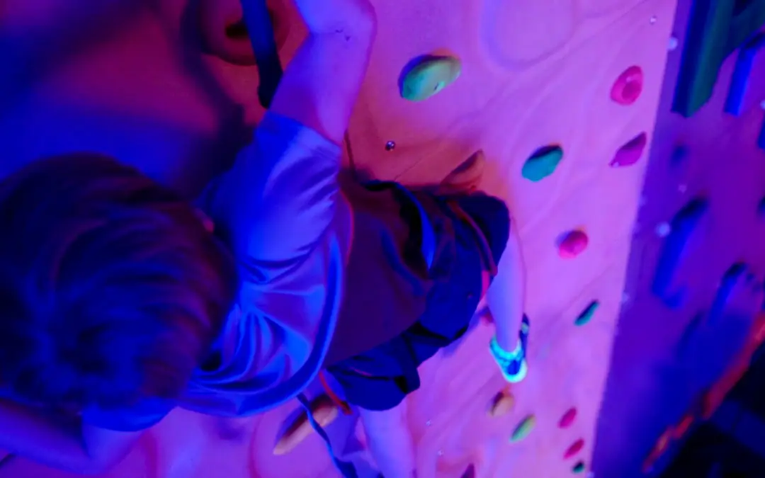 Child climbing the illuminated wall at Urban Air west El Paso.