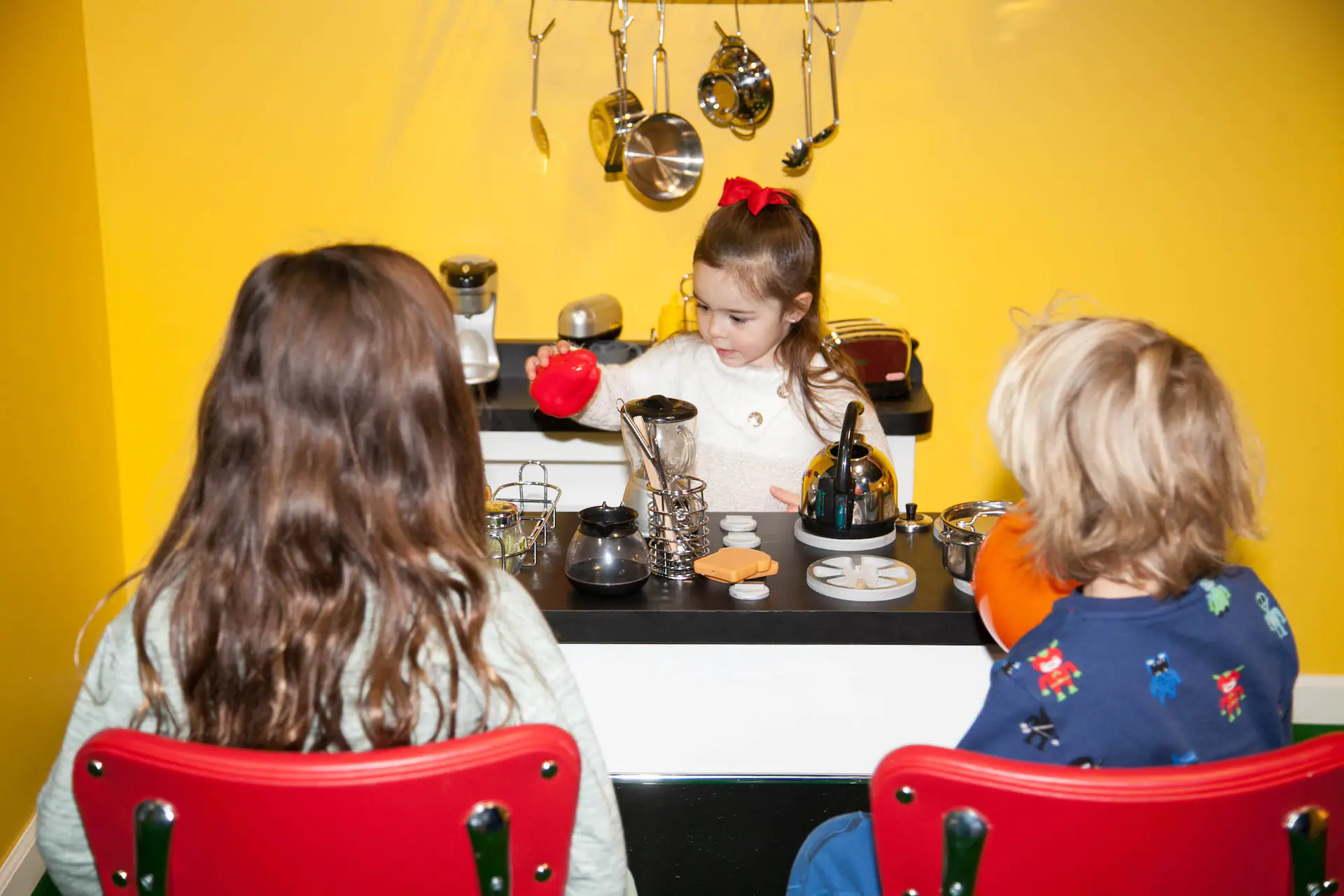 Children playing in the pretend kitchen area at Magic Sky Play.