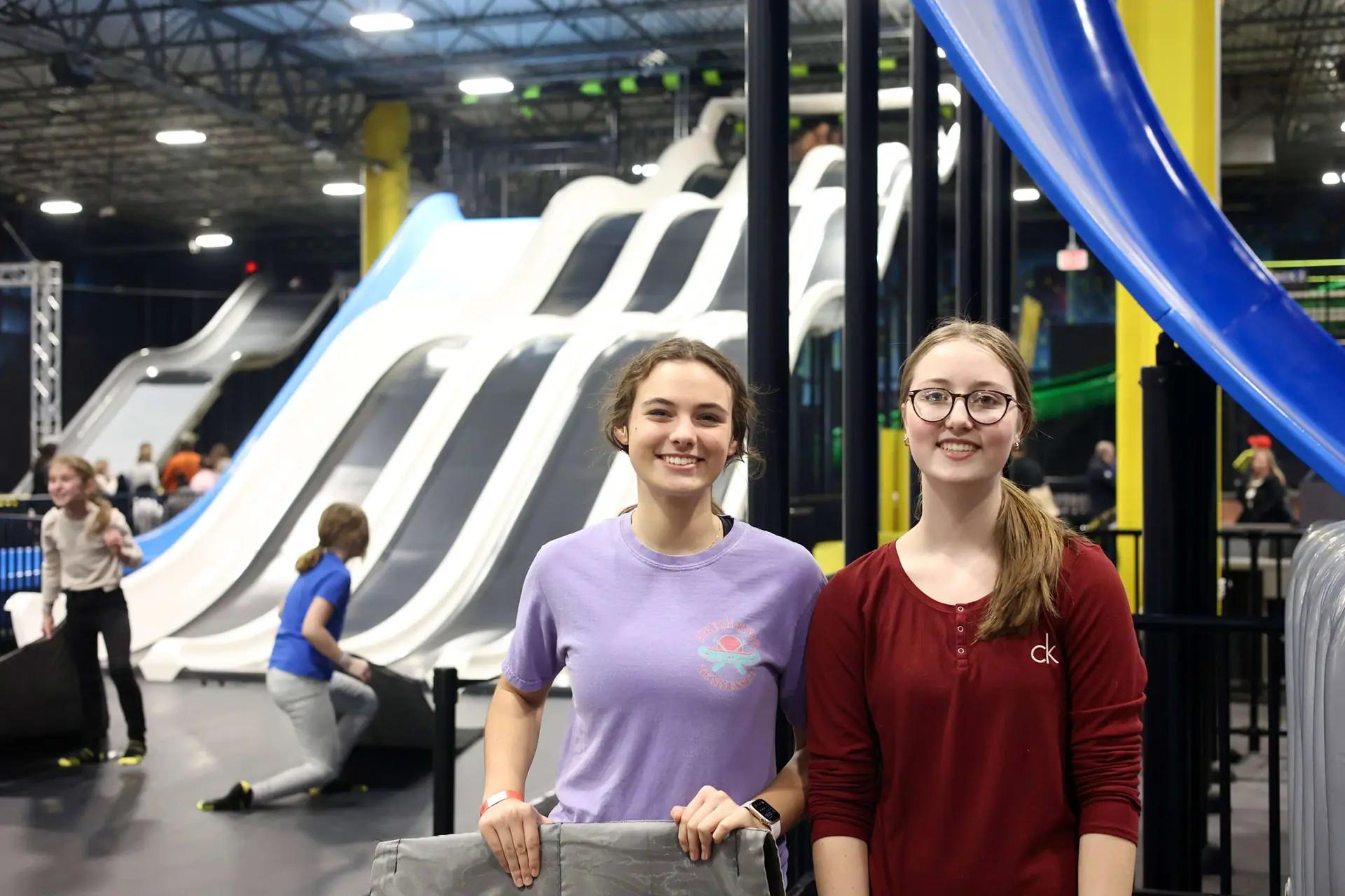 Families playing beneath giant indoor dry slides at Slick City Tulsa.