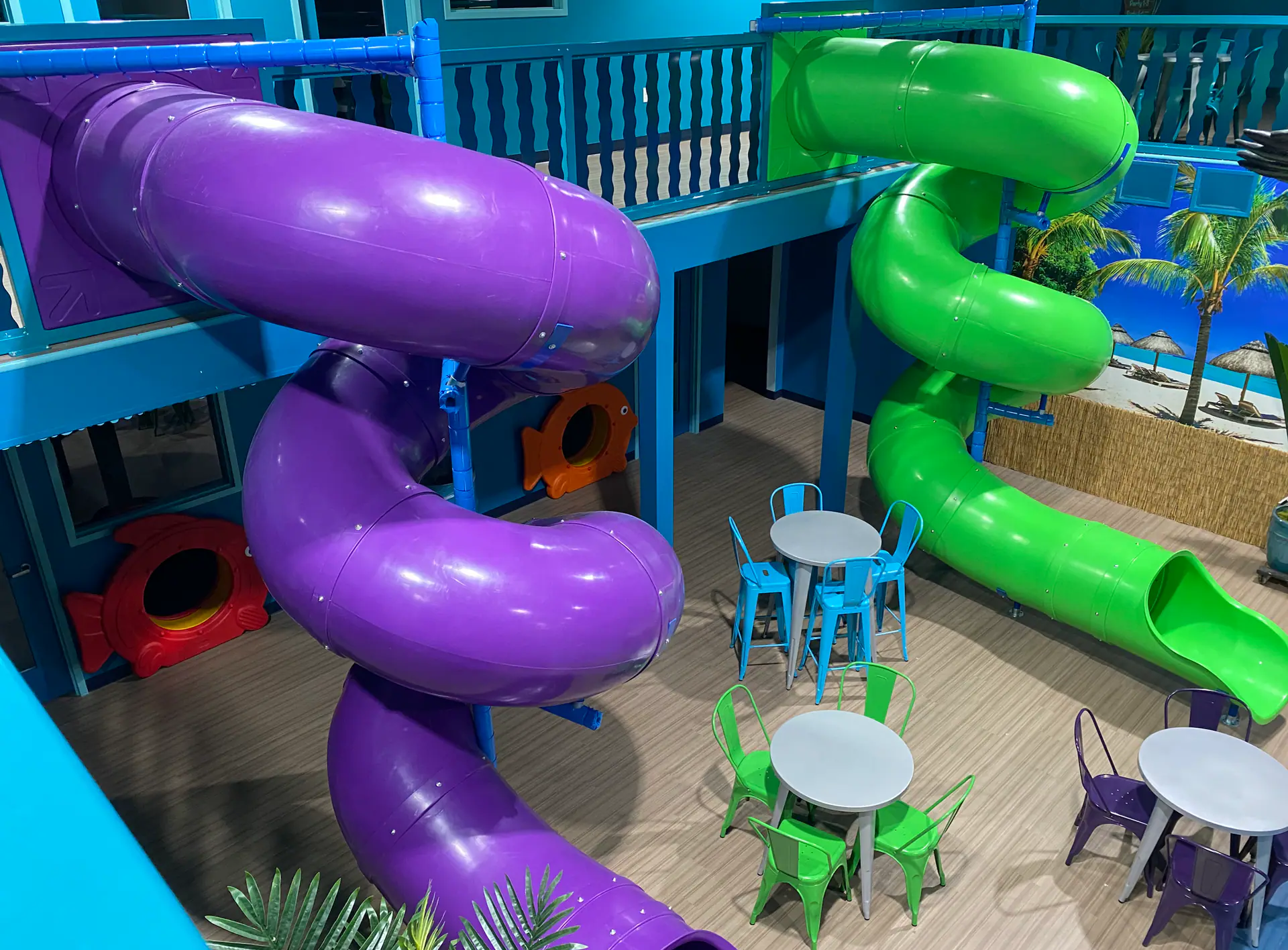 Deep Blue Indoor Play balcony slides overlooking tables and seating.