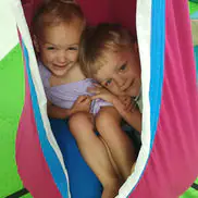 Children in a hanging sensory-style swing at Wild Wonders Playspace.