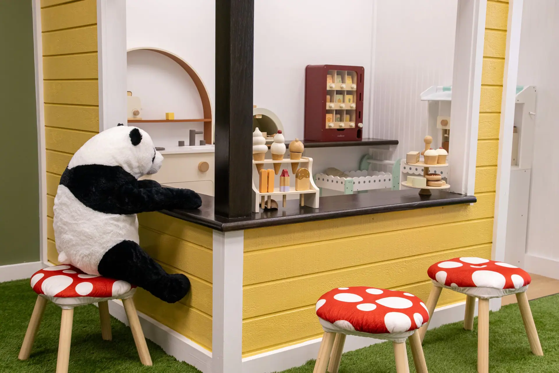 Pretend café counter with mushroom stools and a large stuffed panda at Little Leaps.