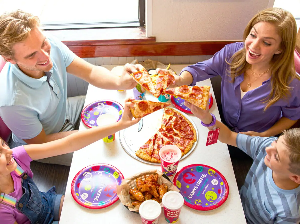 Family sharing pizza and drinks at Chuck E. Cheese.