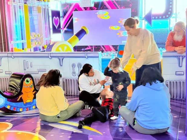 Caregivers and children gathering on the play floor at SuperKidz Club