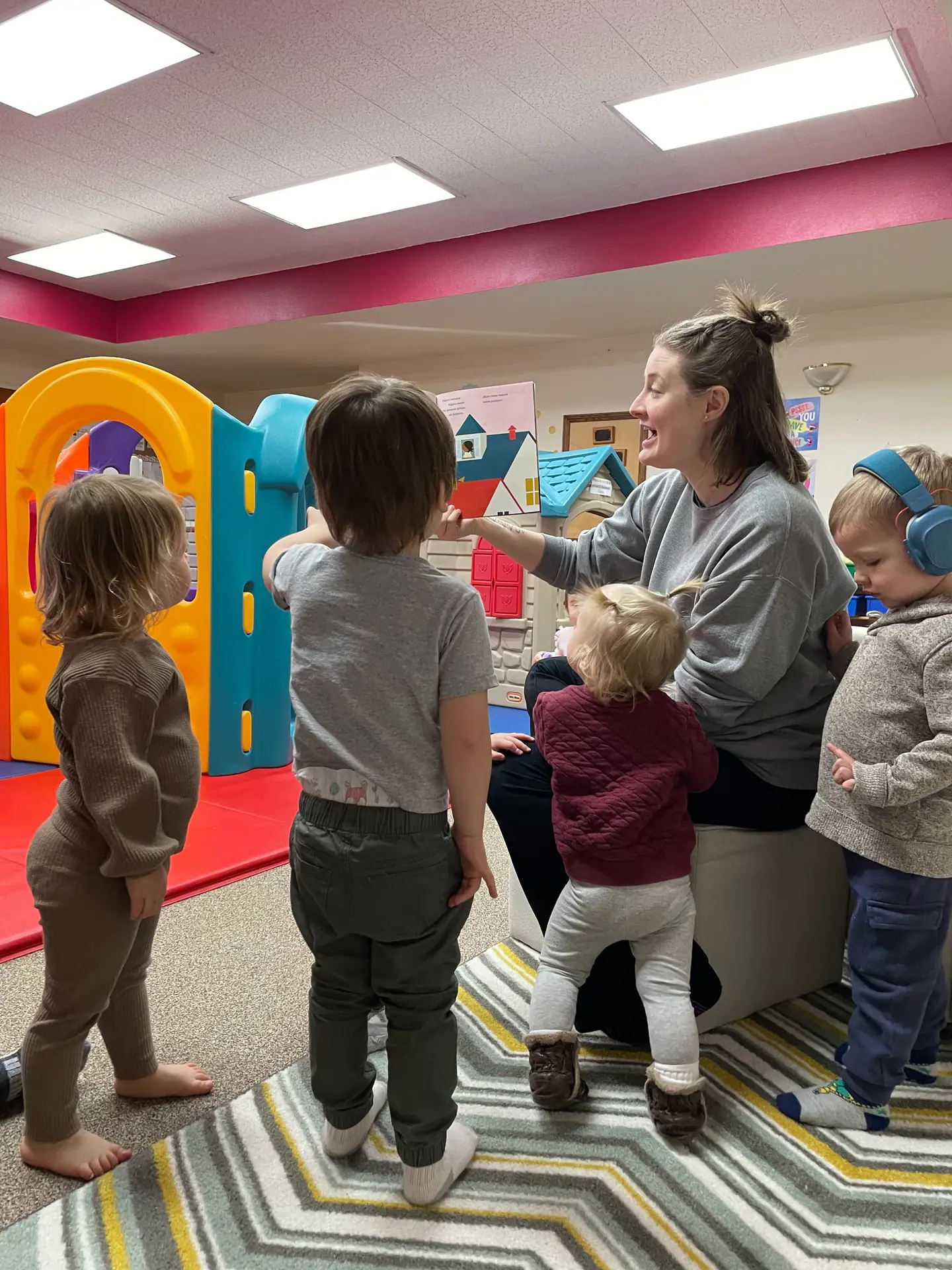 Caregiver-led circle time with toddlers inside Tiny Tots Co-Op.