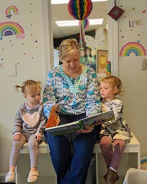 Caregiver reading with two young children inside Island Art Spot